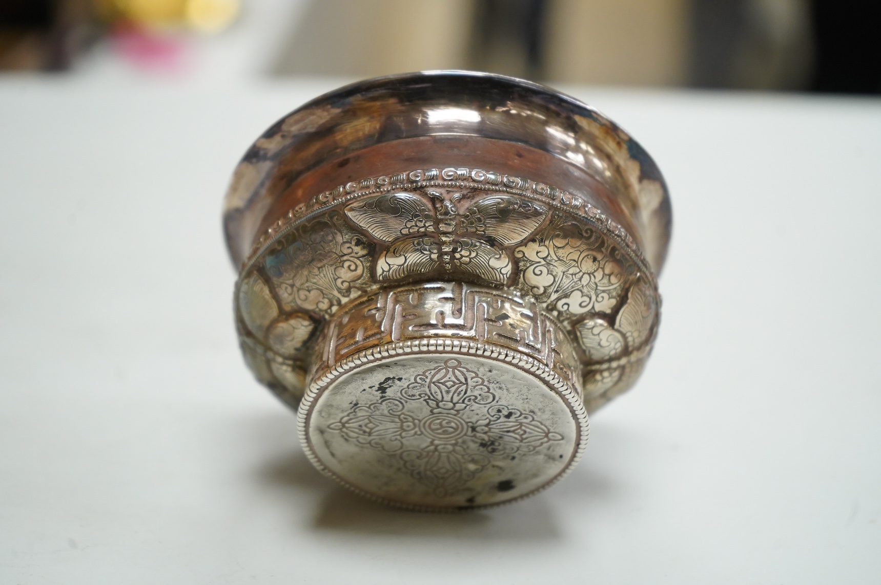 An antique Tibetan white metal mounted burl wood tsampa bowl, on a circular foot, diameter 99mm.
